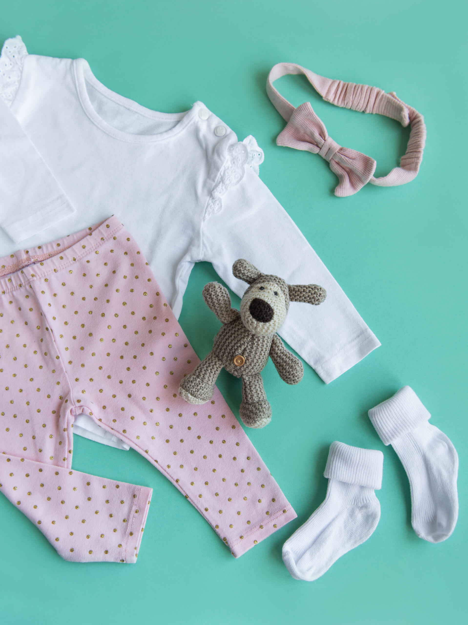 Set of baby bodysuits, pants, socks and knitted toy. Fashion baby clothes and accessories. Flat lay, top view